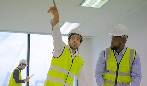 Contractors discussing and gesturing at the ceiling lighting in a commercial office building